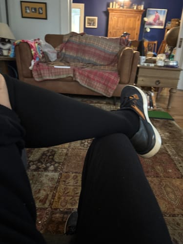 Reviewer sitting indoors with legs crossed, wearing pants and shoes over their Performance Eucalyptus Compression Socks.