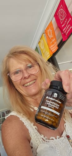 A happy reviewer holds up her bottle of Magnesium + Vitamin D2.