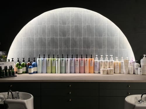 Kundes Katja olivengrønne selvklebende fliser installert som en stilig, bakgrunnsbelyst bue i en salong.