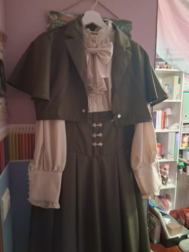 Reviewer's green Victorian dress and cropped cape hanging on a hanger, showing the front clasps.