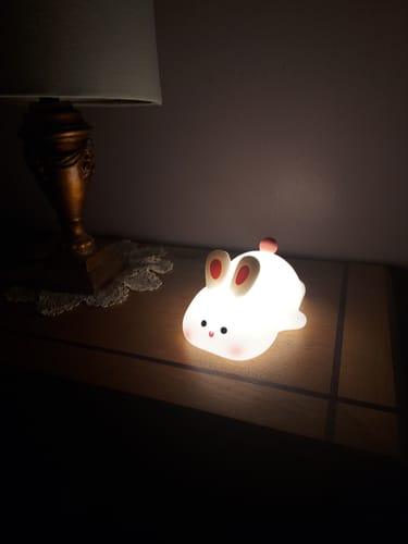 Customer's cute silicone bunny night light glowing softly on a wooden nightstand.