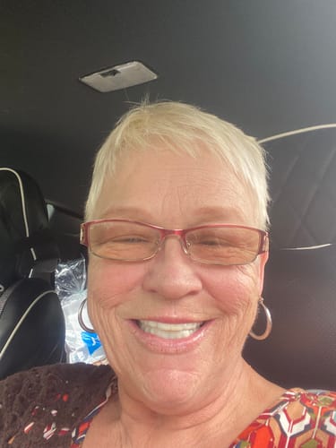Reviewer smiling in a car, showing off her bright, white Pop On Veneers.