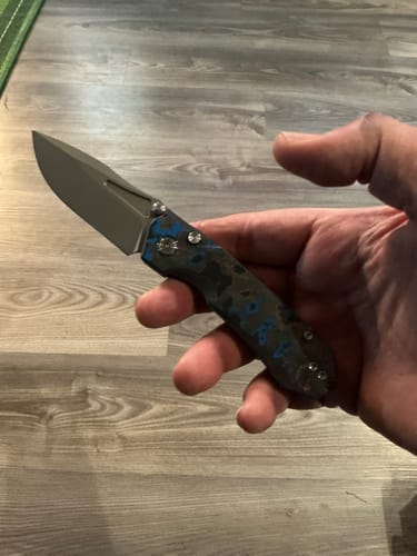 Customer holding their Remette Rhino knife, showing the unique blue and black camo carbon handle and stonewashed blade.