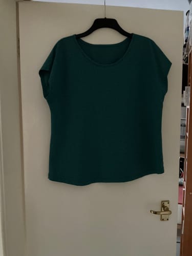 Reviewer's teal top sewn from Melange Cotton Jersey Fabric hanging on a door.