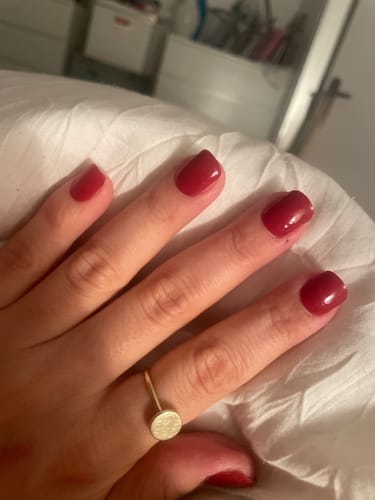 Nahaufnahme der Hand einer Rezensentin, die die satten, roten 'Burning Lava' UV Gel Nail Wraps trägt.