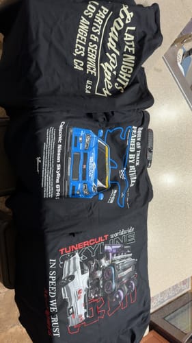Reviewer's three black, car-themed graphic t-shirts from the TCG90 MYSTERY CASH BOX laid out for display.
