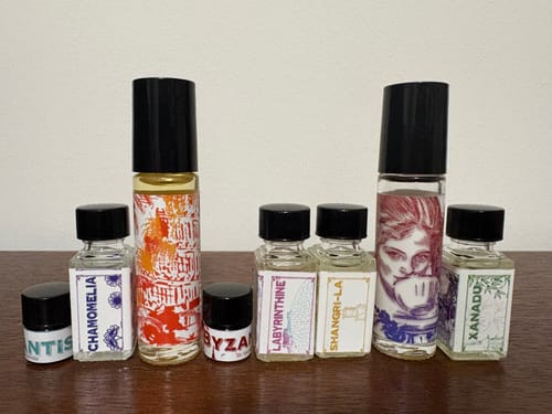 Customer's Chamomelia perfume bottle shown in a collection of various scent bottles on a table.