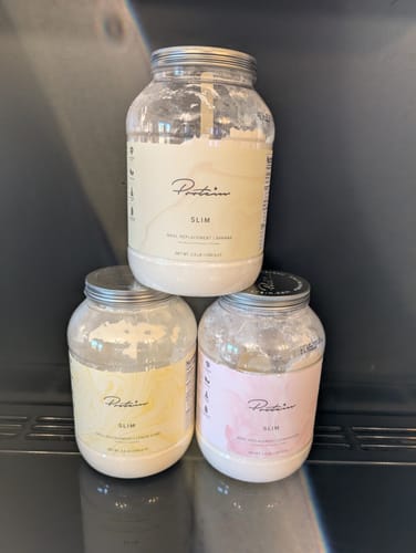 Customer's three tubs of Slim Meal Replacement in Banana, Strawberry, and Lemon Curd flavors, stacked together.