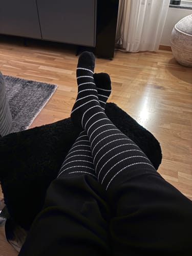 Kund som vilar fötterna iklädd svarta, vitrandiga Diasocks stödstrumpor.