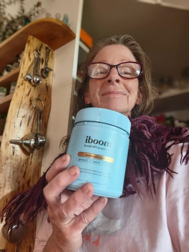 A smiling reviewer holds up a light blue jar from the Festive AM-PM Bundle.