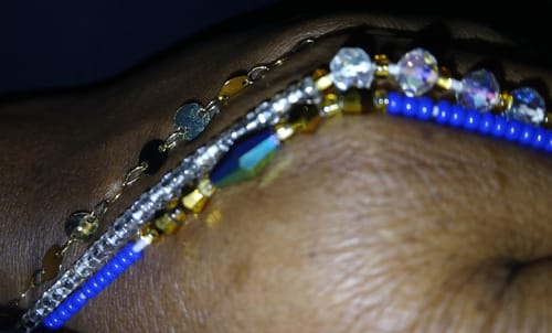 Close-up of a reviewer wearing the beautiful Lux Blue Waist Beads with gold and iridescent accents on their waist.