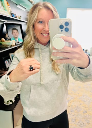 A reviewer taking a mirror selfie, showing the black Emerald Silicone Ring on her finger.