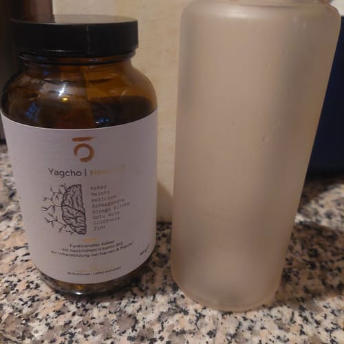 Ein Rezensent zeigt das braune Glas des Anti-Stress Komplexes neben einer Trinkflasche auf einer Küchentheke.