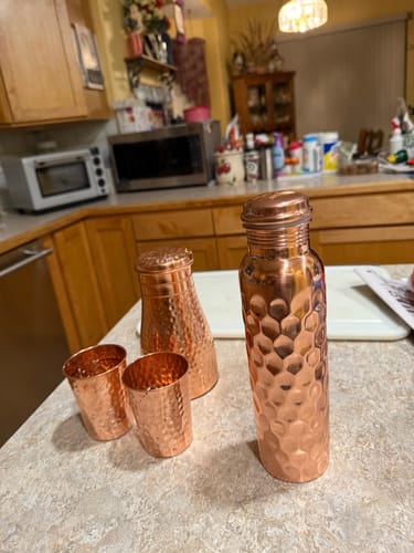 Customer's hammered copper glass set, including a carafe and bottle, displayed on a kitchen counter.