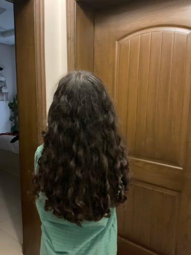 Reviewer from behind showing their long, defined curls after using the Curl Pocket Mini.