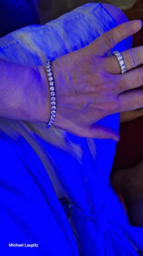 Close-up of a reviewer's hand wearing the sparkly ICY ICICLE RING and a matching bracelet under blue lighting.