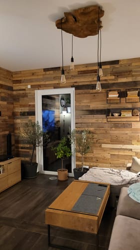 Kundenfoto der montierten NATURA Baumscheibe Deckenlampe, die über einem Wohnzimmertisch vor einer Holzwand hängt.