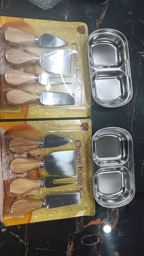 Customer's two 2-section stainless steel saucers placed on a dark surface next to packaged cheese knife sets.