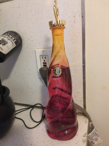 Customer's Chicas Divertidas Blanco Tequila bottle, reused to hold a red liquid, standing on a kitchen counter.