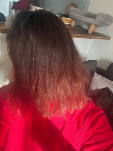 Cliente montrant le résultat du Lissage Indiana Gloss sur ses cheveux, qui sont maintenant lisses et brillants.