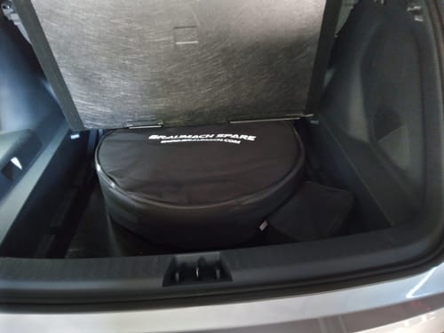 Customer's Spare Wheel in its black carrying bag, fitting inside the trunk compartment of a car.