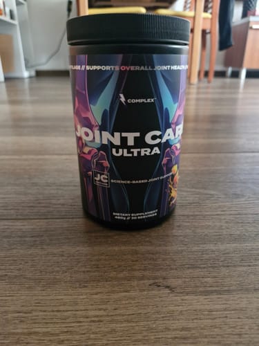 A reviewer's black tub of Complex Joint Care Ultra supplement sitting on a wooden surface.