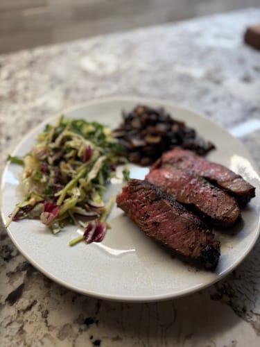 Customer's cooked Bone-In Ribeye, sliced and served with a salad and mushrooms.