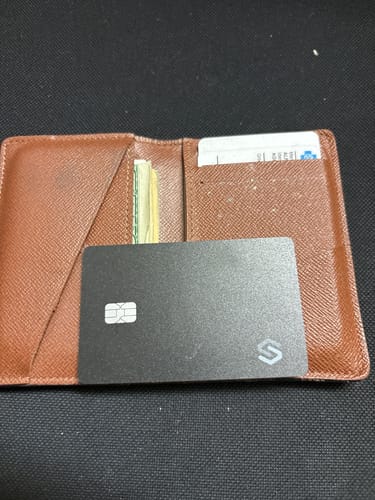 Reviewer's black SPOTMINDERS Tracking Card PRO resting on an open brown wallet.