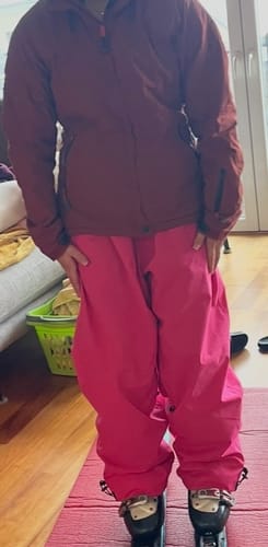 Reviewer trying on the baggy Rose Snow Pants indoors with a ski jacket and boots.