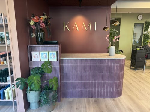 Anmelderens Katja vinrøde selvklebende fliser brukt på en buet kassadisk i en salong.