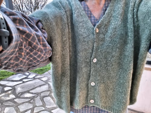 Vue rapprochée d'un client portant le Gilet Claudia vert mousse sur une chemise à carreaux.