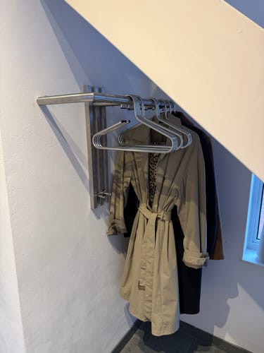 Recensent toont de stalen Senza Wandkapstok die onder een trap is gemonteerd.