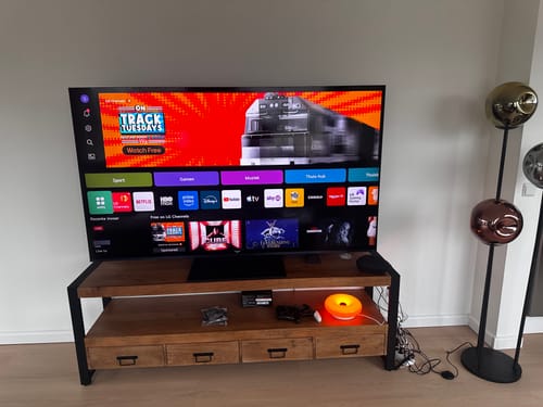 Recensent's houten Tv meubel Sorrento met een grote 75-inch televisie erop in een woonkamer.