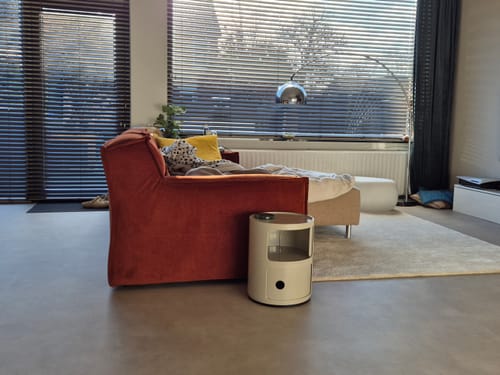 Recensent gebruikt de duifgrijze Kartell Componibili kast als handige bijzettafel naast een bank.