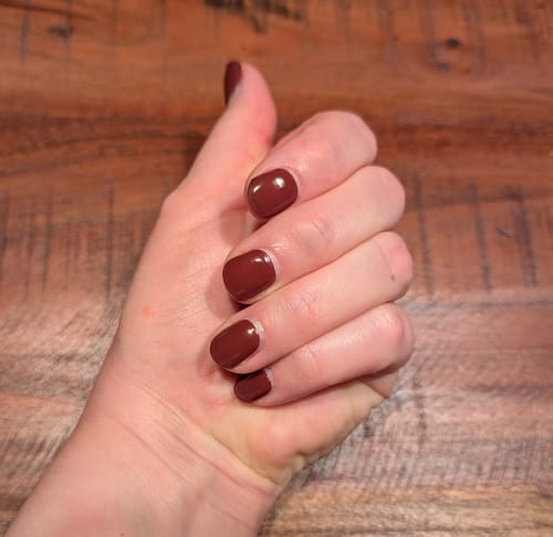 Die Hand einer Kundin mit den aufgetragenen 'Royal Temptation' UV-Gel-Folien in einem glänzenden, tiefen Rot.