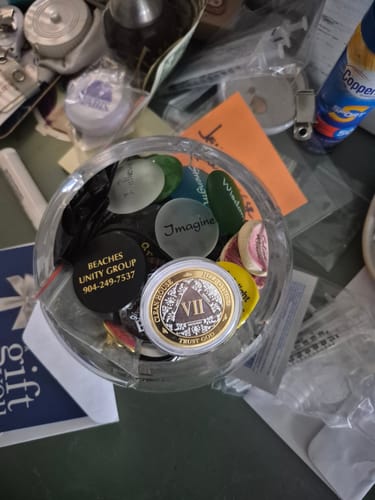 Reviewer's gold and silver 7 Year AA Medallion shown in a glass jar with other sobriety tokens.