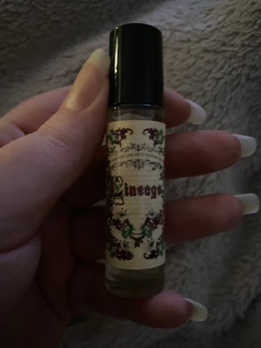 Customer holding the small Lineage roll-on perfume bottle with its intricate label.