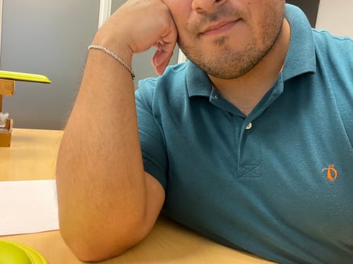 Cliente mostrando la Pulsera Rope 3mm plateada en su muñeca mientras está sentado en un escritorio.