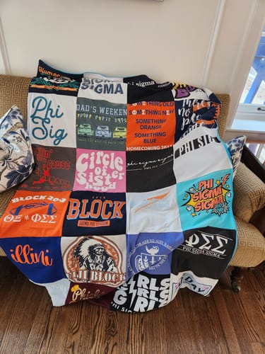 Customer's Premium T Shirt Quilt made from old sorority shirts, draped over a sofa in a living room.