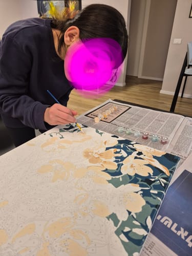 לקוחה מציירת על קנבס מתוך הערכה של צביעה לפי מספרים.