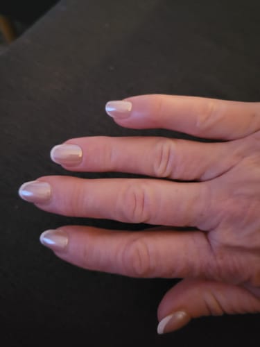 Customer's hand showing the Sugar Coat press-on nails, trimmed to a shorter length with a pearly French manicure design.