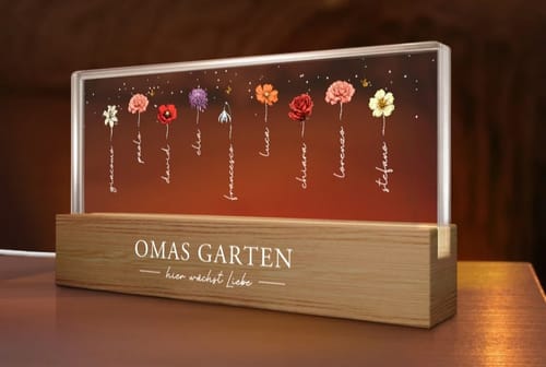 Rezensent zeigt den personalisierten LED-Aufsteller 'Omas Garten'. Er leuchtet mit Blumen und Namen auf einem Holzsockel.