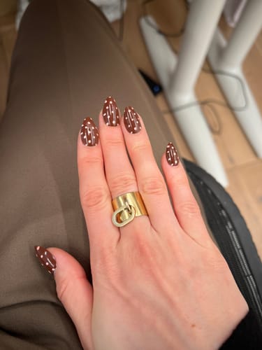 Reviewer's hand showing off the almond-shaped Spot On press-on nails with a brown and white dot design.