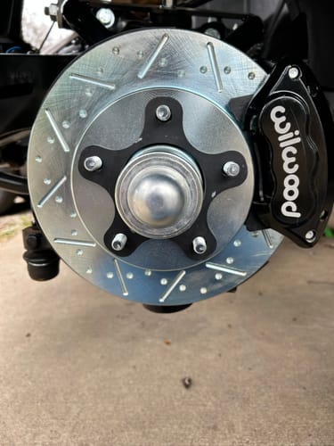 Customer's black Wheel Spacer installed on a car's wheel hub behind a silver drilled brake rotor.