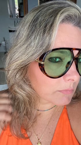 Close-up de uma avaliadora usando os Óculos Tropea com armação tartaruga e lentes verdes.