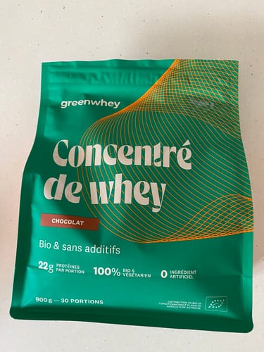 Une cliente montre le sachet vert de sa Protéine de Whey Bio, saveur chocolat.