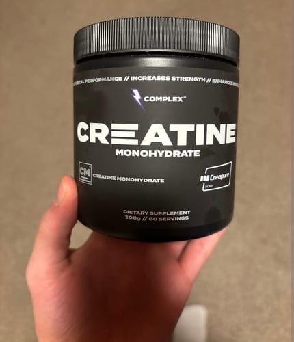 Reviewer holding a black tub of Complex Creatine Monohydrate.