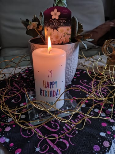 Rezensent zeigt die brennende, personalisierte 'Happy Birthday'-Kerze für einen 79. Geburtstag.