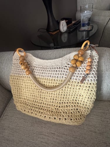 Customer's completed Sunny Beach Tote in an ombre yellow, featuring wooden beaded handles and resting on a couch.