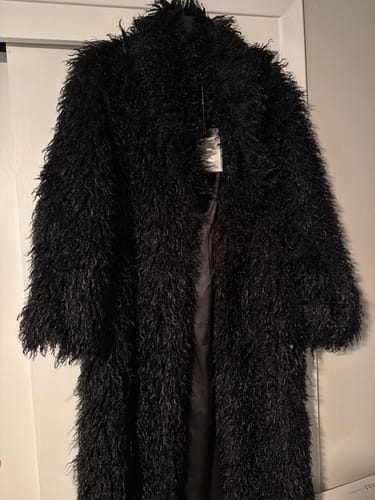 Customer's black, shaggy Faux Fur Plush Long Coat hanging on a door, showing the texture and lining.
